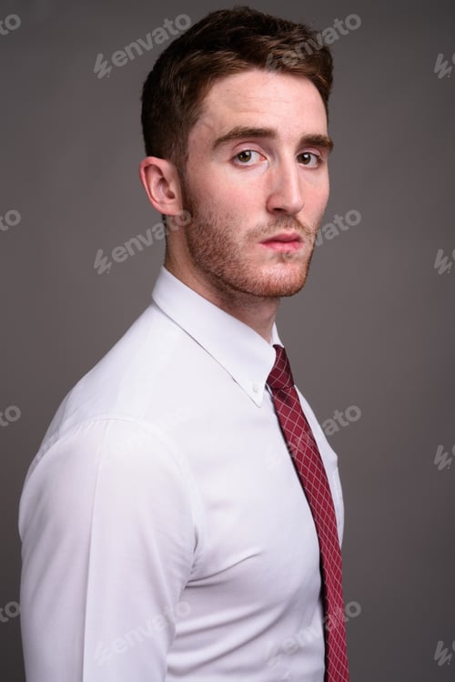 Preview: Portrait of young handsome businessman against gray background