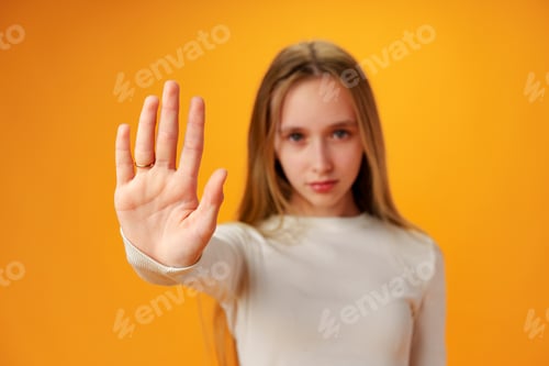 Preview: Teen girl extend hand in block gesture against yellow background