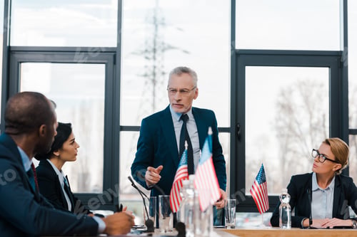 Preview: selective focus of bearded businessman pointing with finger at african american diplomat near