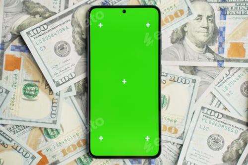 Preview: Smartphone with green screen on pile of dollar banknotes, top view