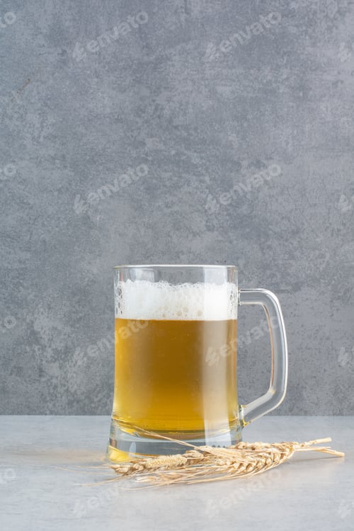 Preview: A glass of delicious beer with wheat on hay background