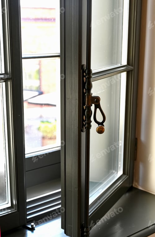 Preview: Close-up of a vintage metal window lever. Brass handle on the old wooden window