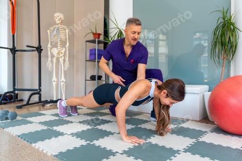 Preview: Woman Doing Push-up With Trainer Assisting Her