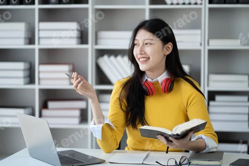 Preview: Happy young Asian woman working while reading book in the study room.