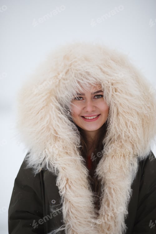 Preview: young beautiful girl in a fashionable coat enjoying the first snow on the cityscape