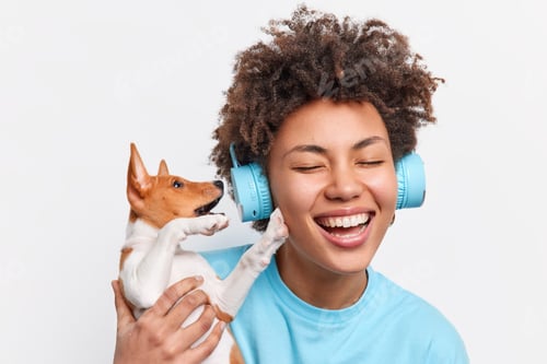 Preview: Headshot of curly haired cheerful teenage girl with closed eyes toothy smile holds puppy dog wears w