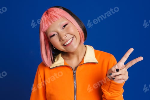 Preview: Asian girl with pink hair laughing while showing peace gesture