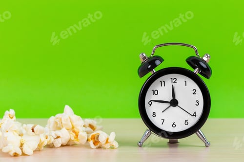 Preview: Popcorn and small alarm clock on pastel green background minimal creative concept. Space for copy