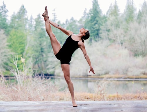 Preview: Woman in black leotard dancing gracefully by a serene forest lake. USA