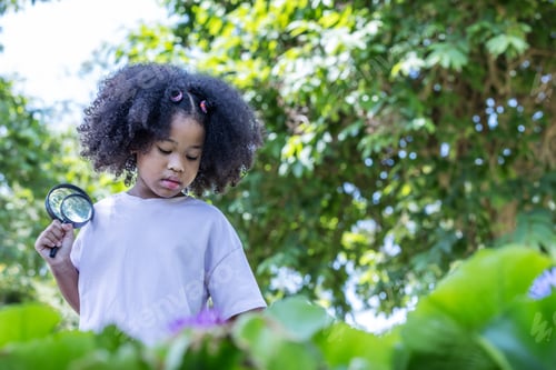 Preview: A thoughtful young girl holds a magnifying glass while observing plants in a lush green garden.