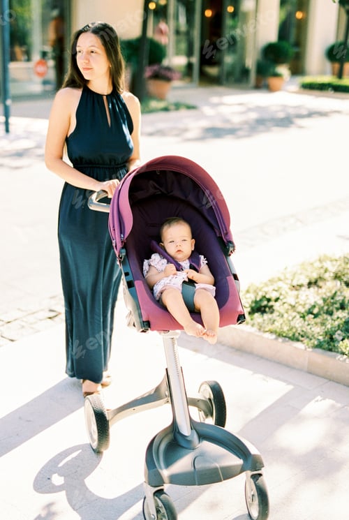 Preview: Mom with a baby in a stroller stands on the sidewalk