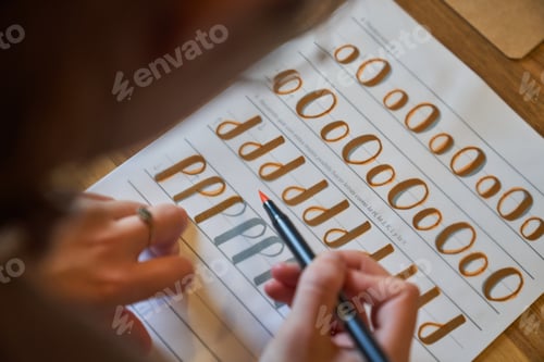 Preview: Crop person practicing lettering using orange felt pen