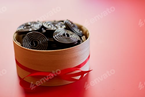 Preview: Tasty black liquorice candies in present box on red background