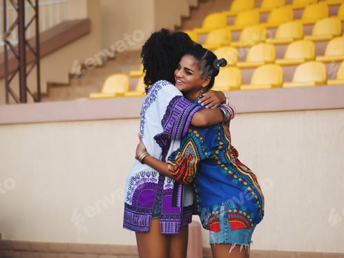 Preview: African American women hugging in meeting or date. Friends in traditional clothes