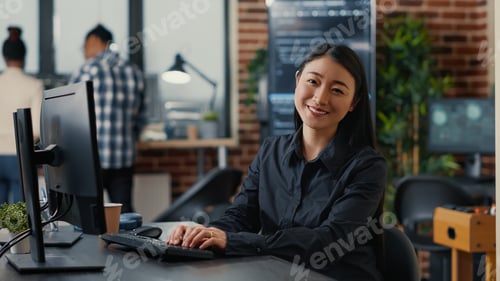 Preview: Smiling asian database software developer writing programming code on computer keyboard