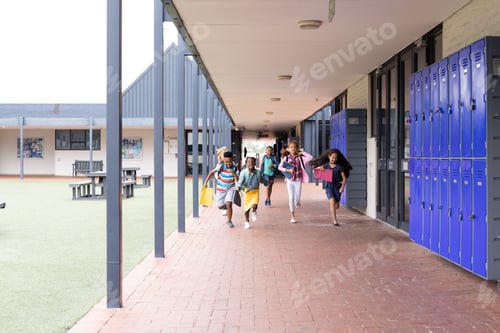 Preview: Happy, diverse children running in elementary school corridor, copy space