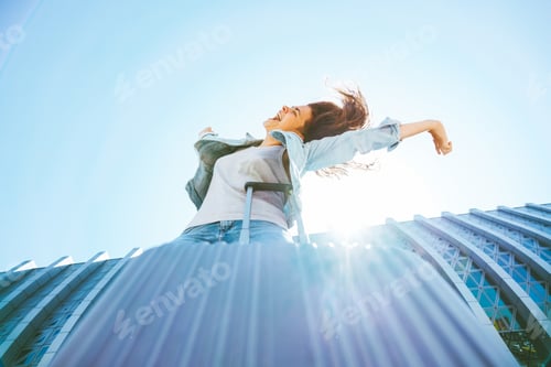 Preview: Beautiful happy young woman joyfully reaches for the sky