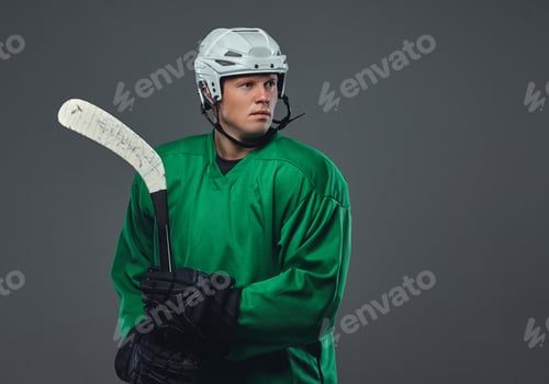 Preview: Hockey player wearing black protective uniform holds a hockey stick on a gray background.