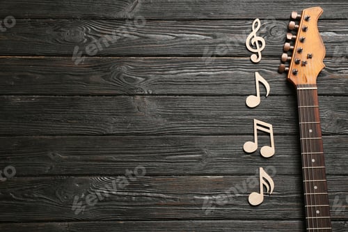 Preview: Music notes and guitar neck on wooden background, top view. Space for text