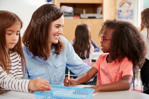 Preview: Female primary school teacher and girls in class, close up