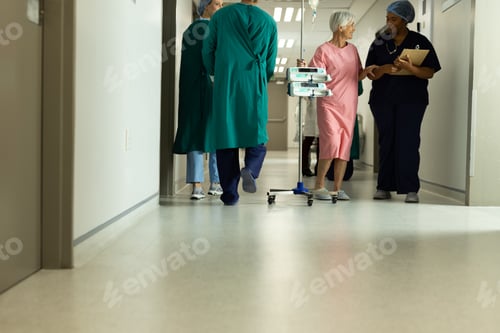 Preview: Diverse female doctor and caucasian senior female patient with iv pole talking in hospital