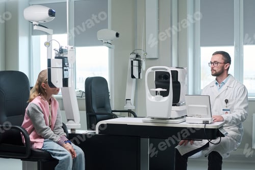 Preview: Girl Undergoing Eye Examination with Male Optometrist in Clinic