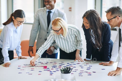 Preview: Laughing businesspeople trying to solve a puzzle in an office