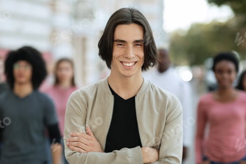 Preview: Cheerful young man standing over multiracial crowd on street