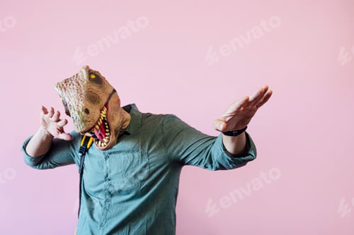 Preview: Man with lizard mask on pink background celebrating elated.