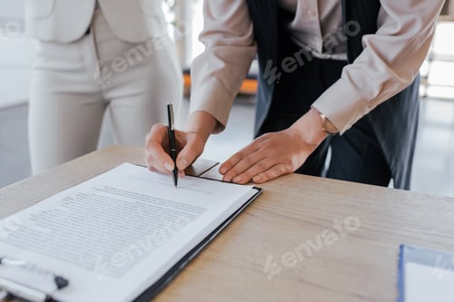 Preview: cropped view of businesswoman signing contract near coworker