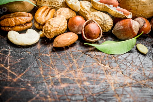 Preview: Nuts background. Different kind of nuts with green leaves.