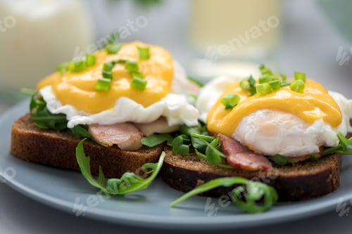Preview: Close up eggs Benedict with arugula, bacon and hollandaise sauce on gray wooden background