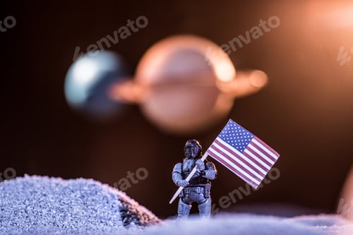 Preview: selective focus of toy astronaut holding american flag in space
