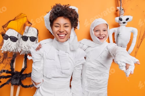 Preview: Positive mother and child have fun during halloween celebration look happily at camera feel carefree
