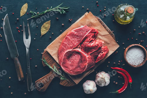 Preview: top view of raw steak on parchment paper and cutting board with spices and cutlery around