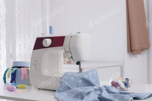 Preview: Modern sewing machine, fabric and accessories on table indoors