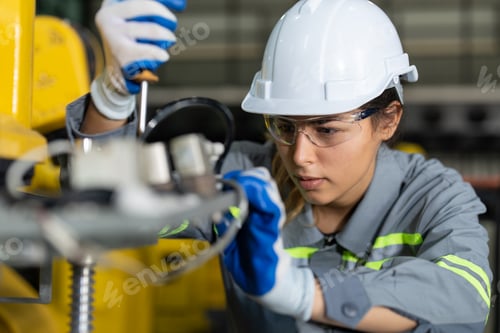 Preview: Female engineer checking and maintaining robot arms machine at factory