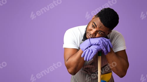 Preview: Exhausted Black Guy Leaning On Mop Handle, Resting After Cleaning