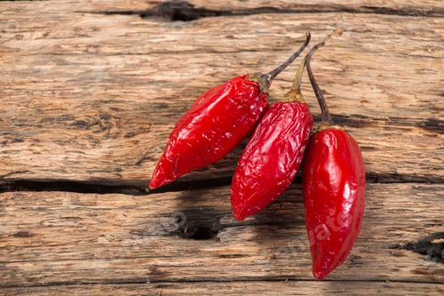 Preview: three red chili peppers on rustic wooden background