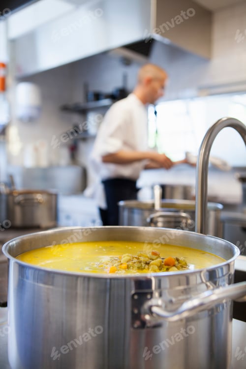 Preview: Close-up of food in utensil with chef in background