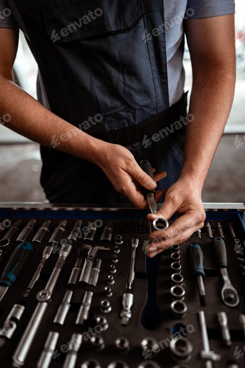 Preview: Tools are organized on a workbench as a person prepares for mechanical work on a vehicle