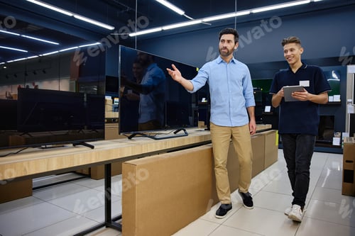 Preview: A Friendly Tech Store Interaction A salesperson actively assisting a customer with various TVs