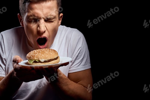 Preview: Man with hamburger plates on black background in white t-shirt portrait cropped view of fast food