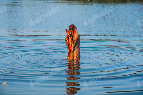 Preview: Traditionally dressed Indian woman pray into the river on Chhat Puja Festival.