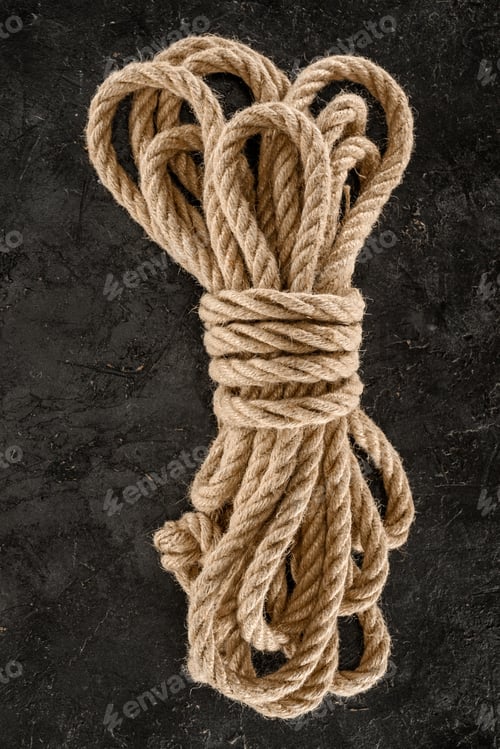 Preview: top view of tied brown nautical rope on dark concrete tabletop