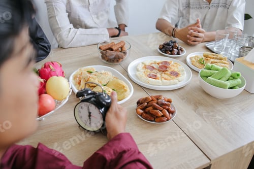 Preview: Various Food Served on The Dining Table During Ramadan. Muslim Man Holding Clock Waiting For Iftar.