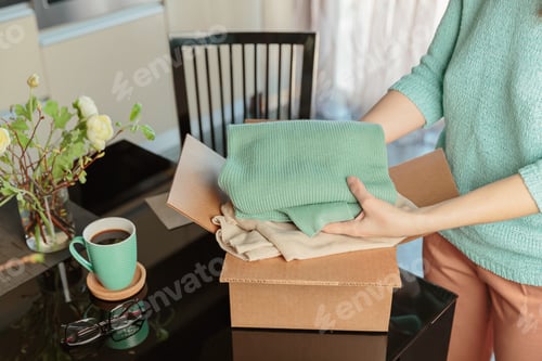 Preview: Woman packing box with used wardrobe for resale