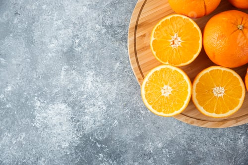 Preview: A wooden board full of juicy slices of orange fruit on stone background