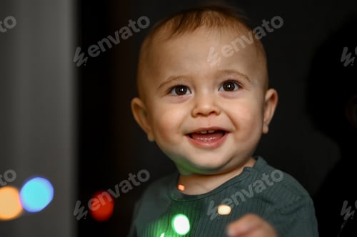 Preview: Portrait of a one-year-old baby, the child plays with a glowing garland