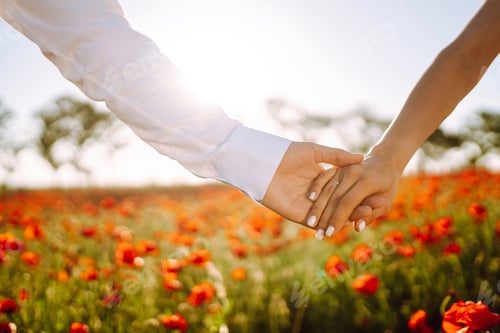 Preview: Holding hands of happy young couple having fun in poppy field. Love. Together